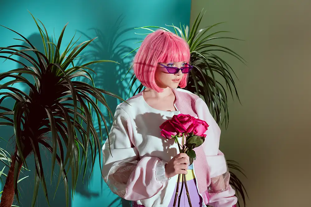 Fashionable woman with pink hair holding roses in tropical setting