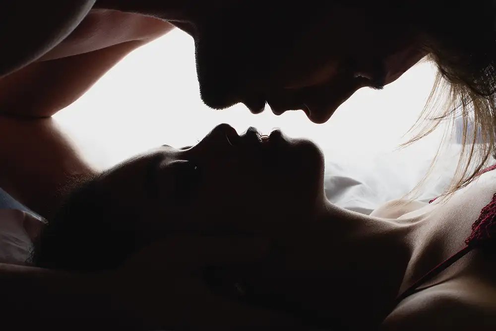 Silhouetted couple in intimate embrace on a bed